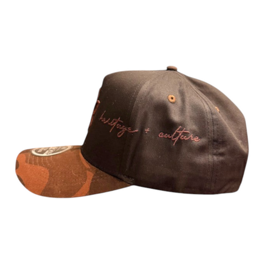 KA'EO Apparel brown snapback hat featuring a camo brim and embroidered heritage + culture text on the side panel.