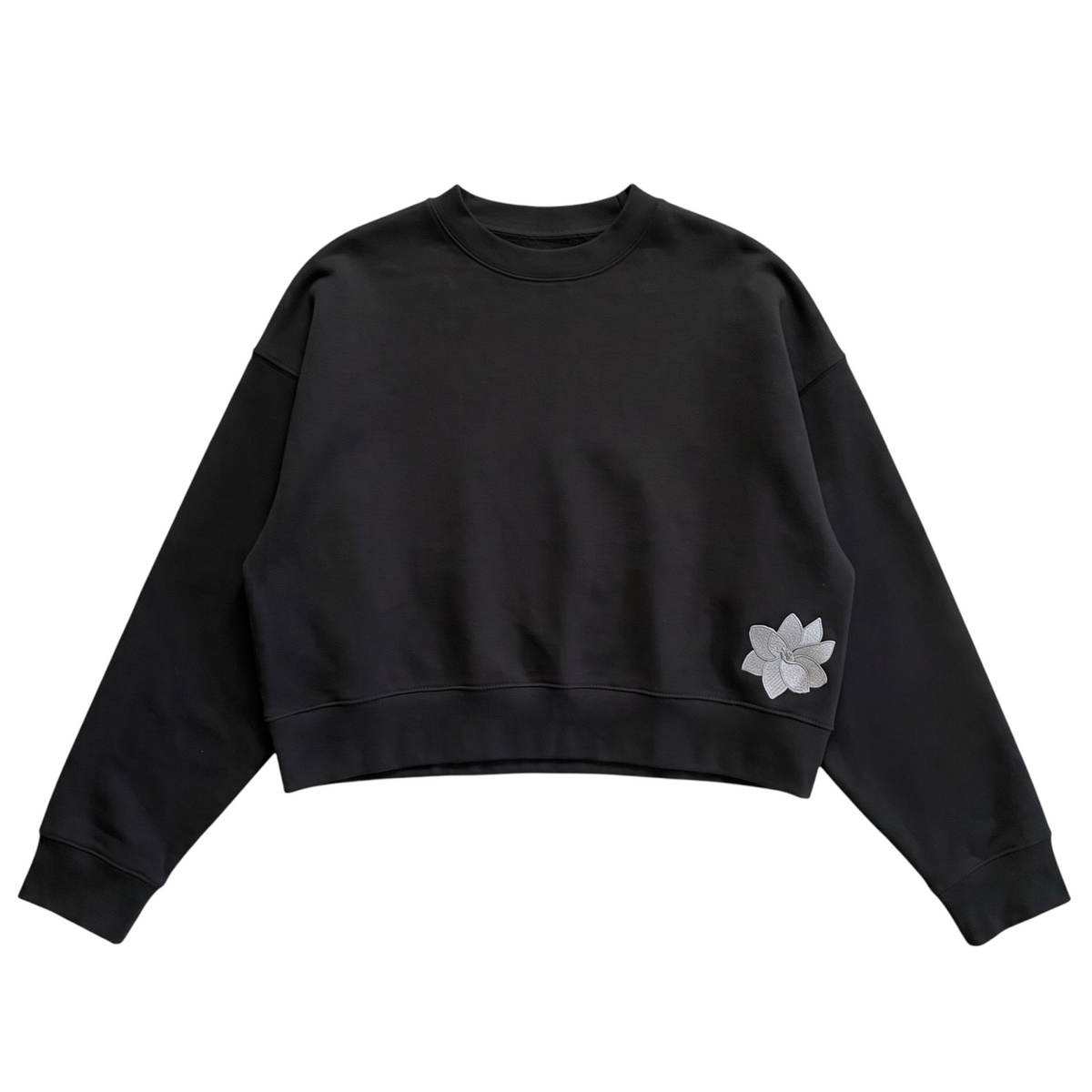 KA'EO Apparel black relaxed cropped fleece crewneck sweatshirt with embroidered Sampa flower detail on the hem.