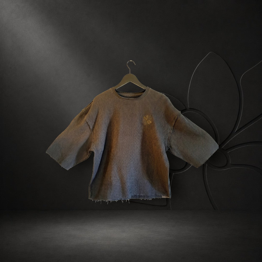 KA'EO Apparel black cropped waffle knit Sampa top with short sleeves and subtle chest embroidery on a hanger.