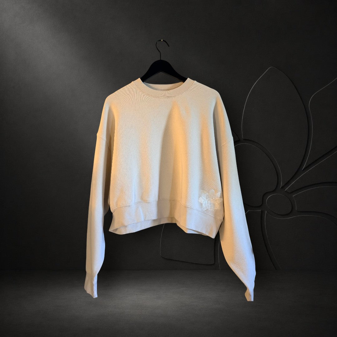 KA'EO Apparel cream relaxed cropped crewneck fleece sweatshirt with delicate floral embroidery on a hanger.