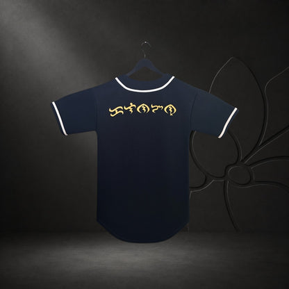 KA'EO Apparel black baseball jersey featuring gold Baybayin script on the back with white piping on a hanger