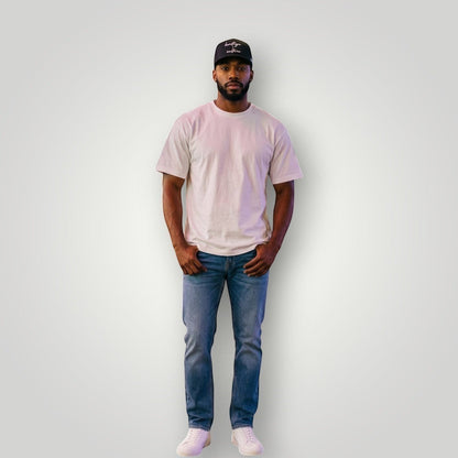 KA'EO Apparel black cotton baseball cap with embroidered "heritage + culture" text and KA'EO logo on side. Model wears cap with white t-shirt and jeans.