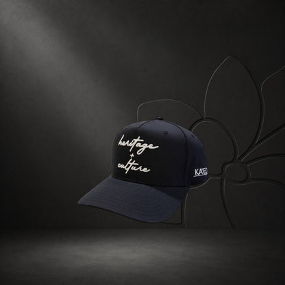 KA'EO Apparel black cotton baseball cap with embroidered 'heritage + culture' script and side branding.