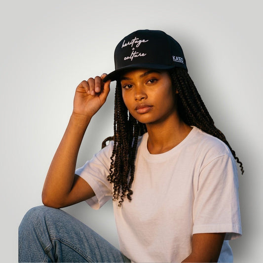 KA'EO Apparel black cotton baseball cap with embroidered "heritage + culture" script and side branding. Curved brim, structured fit.