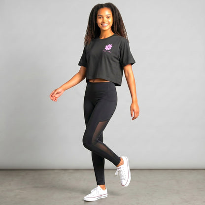 KA'EO Apparel black cropped t-shirt with pink Sampaguita graphic and script text. Model wears black leggings and white sneakers.