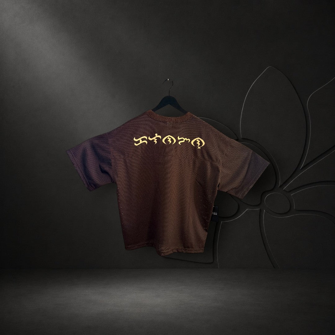 KA'EO Apparel brown mesh cropped football jersey with gold Baybayin script on the back hanging on a door