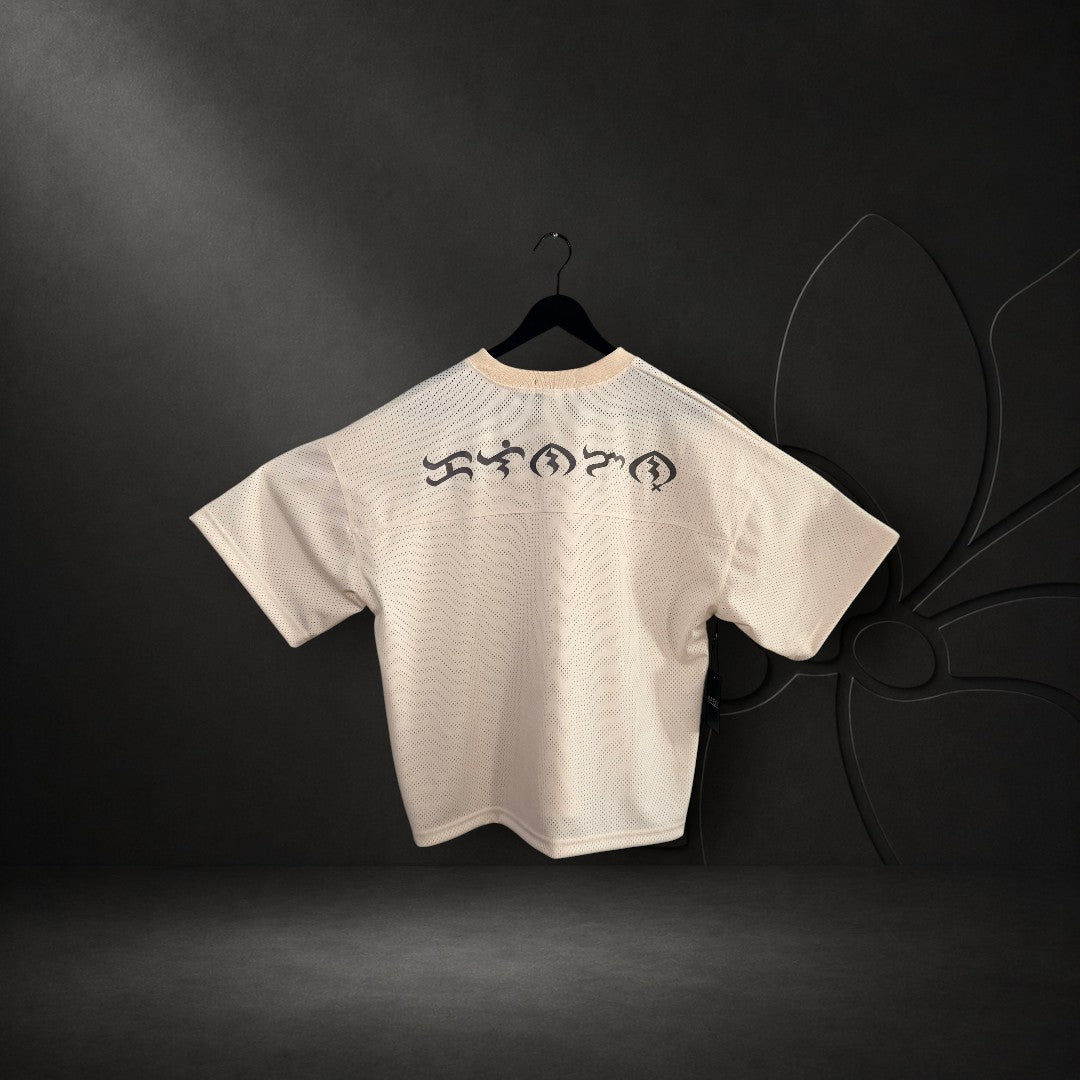 KA'EO Apparel cream mesh cropped football jersey featuring black Baybayin script on the back, hanging on a door.