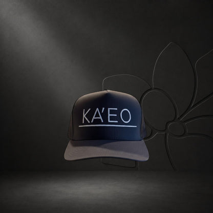 KA'EO Apparel dark grey trucker hat with white embroidered logo and mesh back panels.