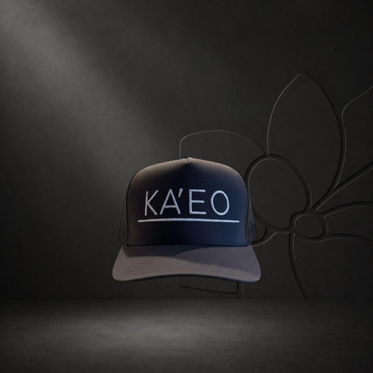 KA'EO Apparel dark grey trucker hat with white embroidered logo and mesh back panels.