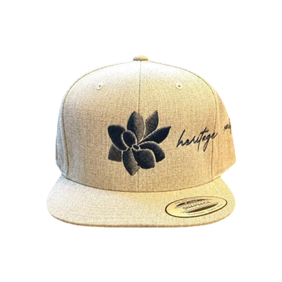 KA'EO Apparel heathered tan snapback hat with embroidered dark gray sampaguita flower and "heritage + culture" script.