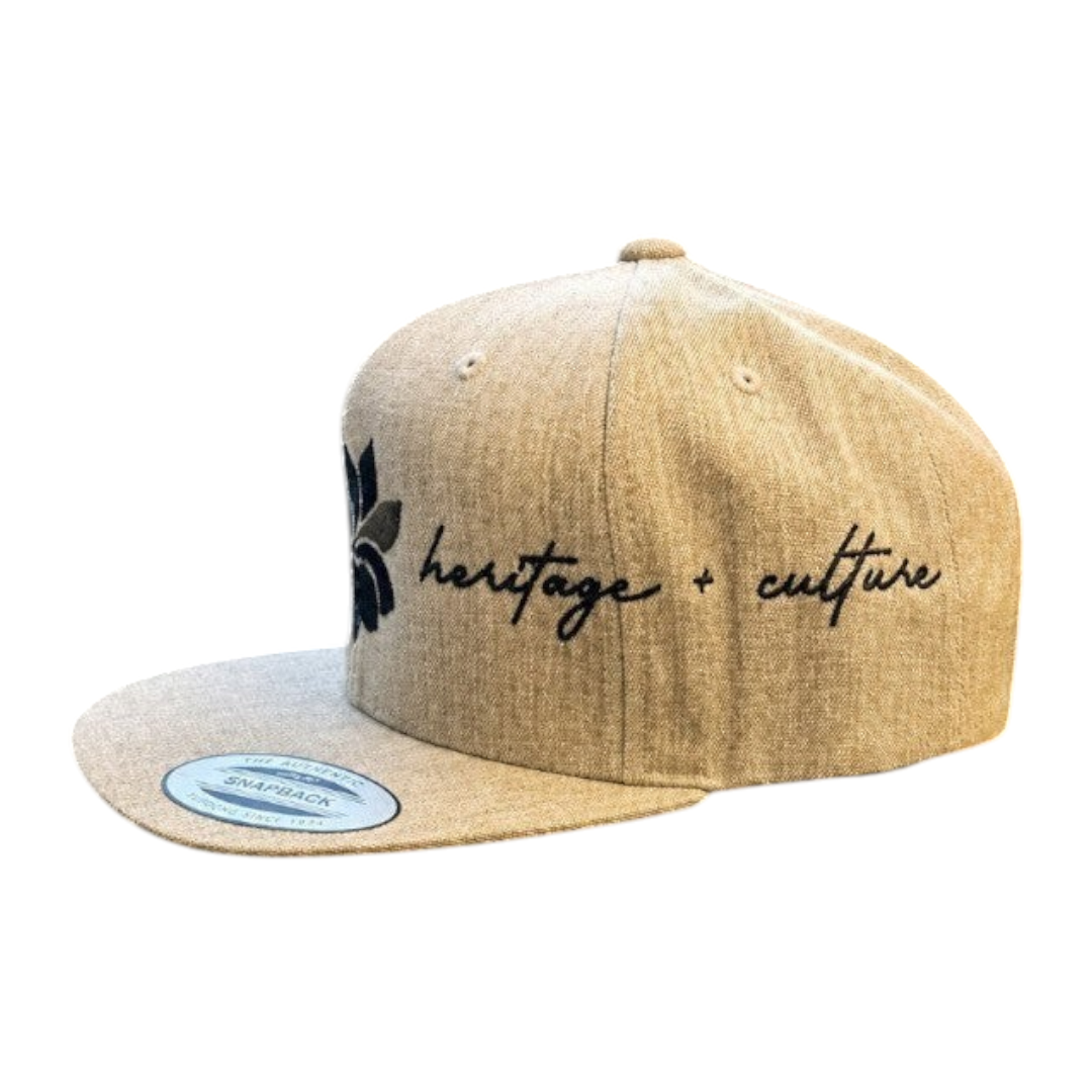 KA'EO Apparel heathered tan snapback hat with embroidered dark gray sampaguita flower and "heritage + culture" script.