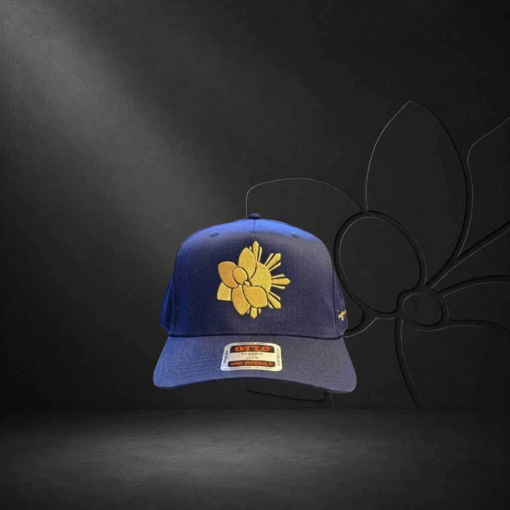 KA'EO Apparel navy blue snapback hat with gold embroidered Sampa-Sol symbol and "heritage + culture" script.