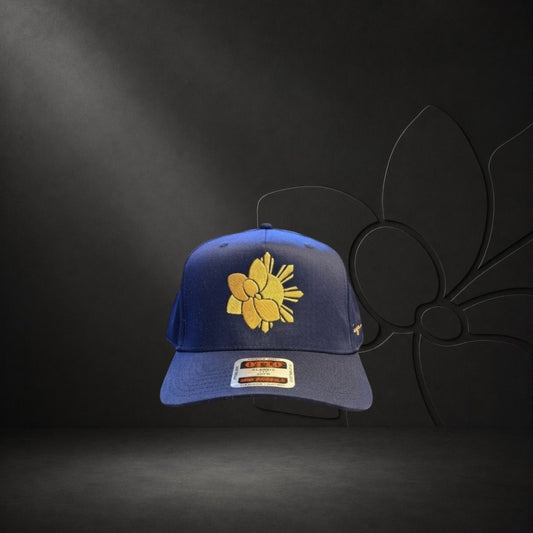 KA'EO Apparel navy blue snapback hat with gold embroidered Sampa-Sol symbol and "heritage + culture" script.