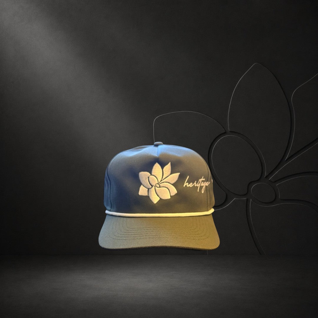 KA'EO Apparel olive green baseball cap with white embroidered Sampaguita flower and "heritage" text. Features a cream rope detail