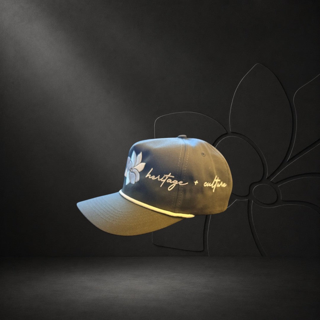 KA'EO Apparel olive green baseball cap with white embroidered Sampaguita flower and "heritage + culture" text.