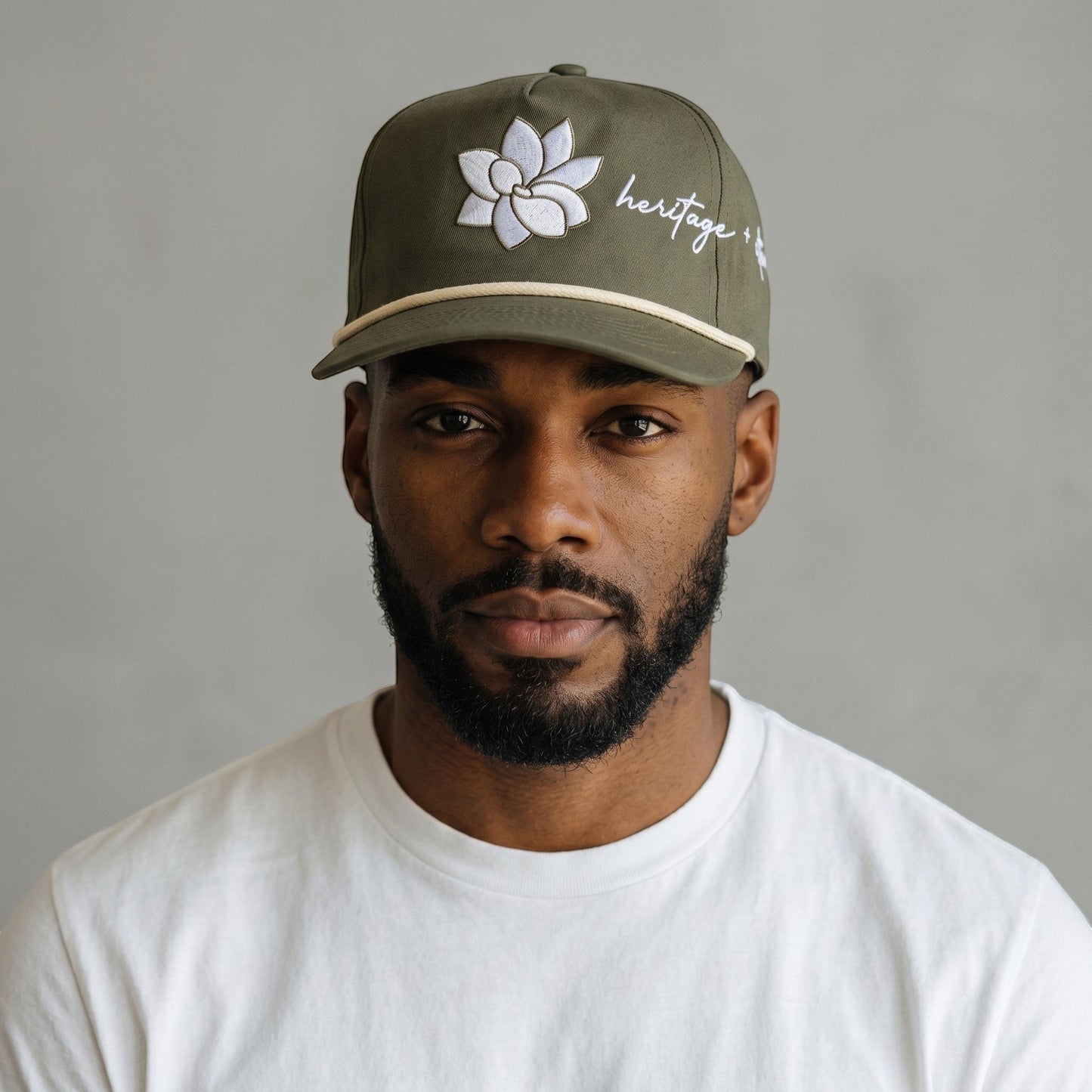 KA'EO Apparel olive green baseball cap with embroidered Sampaguita flower and "heritage + culture" text.